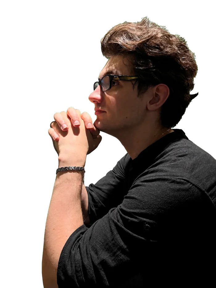 Side-profile portrait of Morflight wearing glasses with his hands clasped